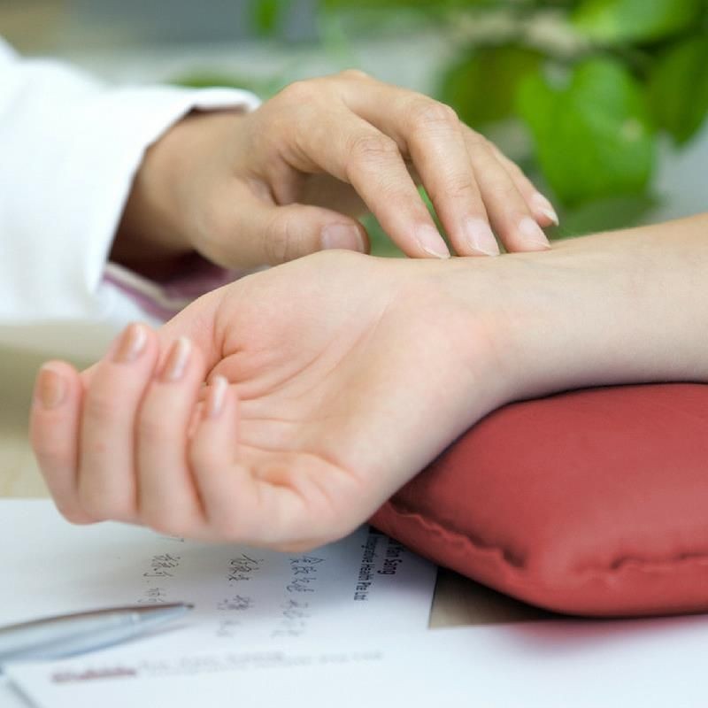 Close-up of a doctor checking the pulse on a patient's wrist during a medical consultation.