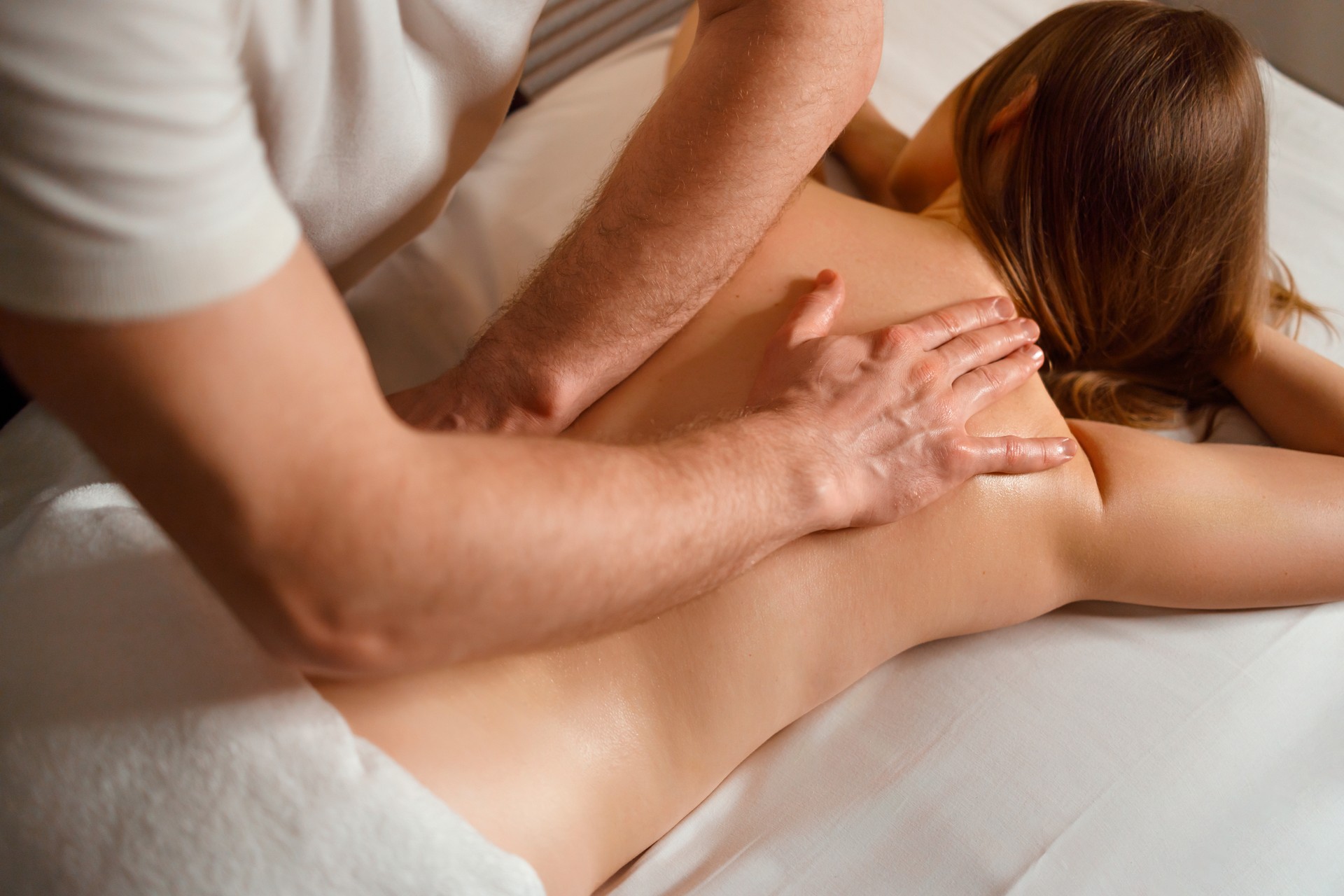 Masseur gives a therapeutic back massage to a young woman