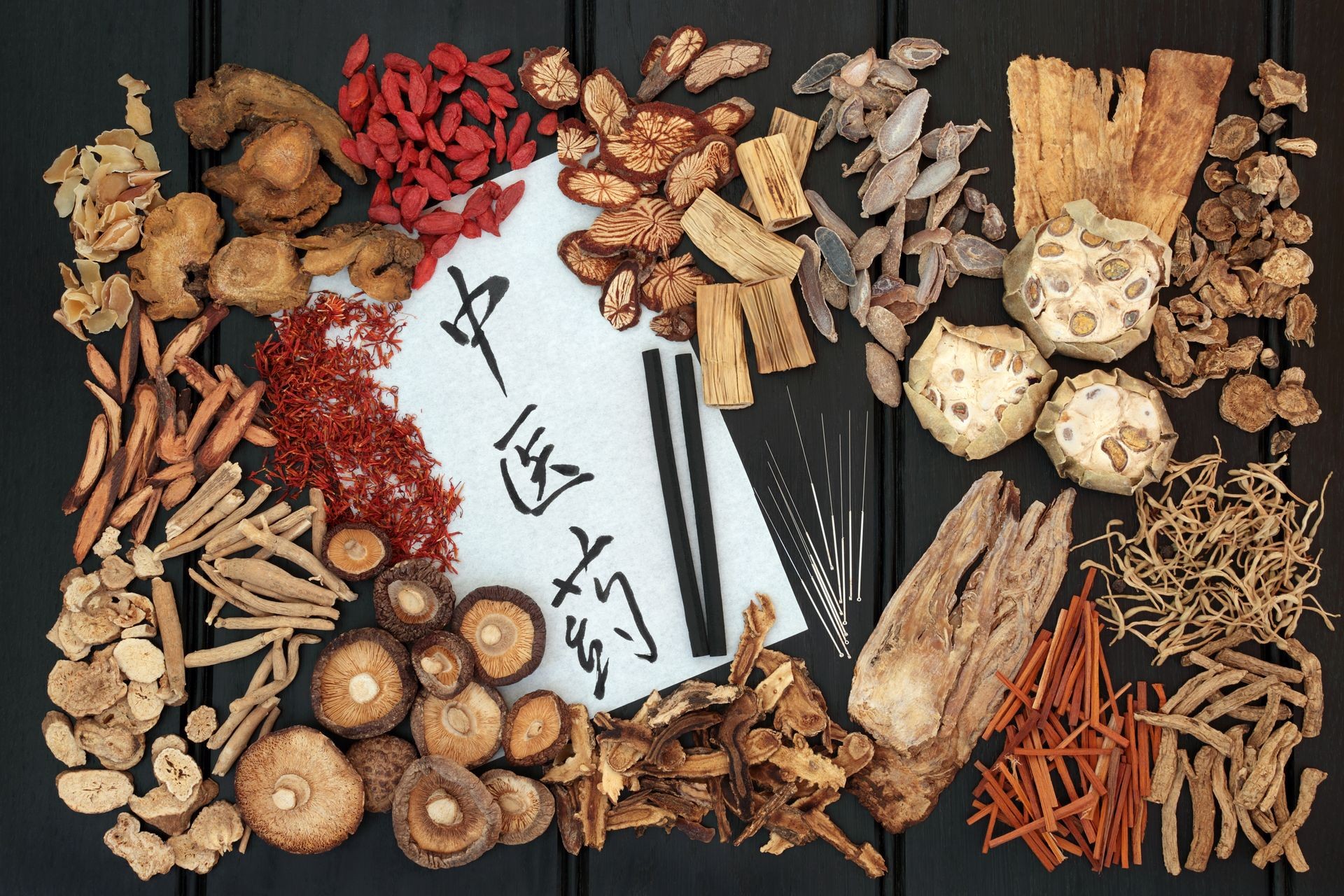 Herbal and moxa sticks used in moxibustion with traditional herbs and calligraphy script on rice paper. Translation reads as chinese herbal medicine. Top view on wood background. 